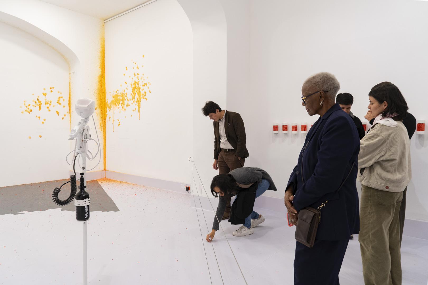 Robotic arm marking orange dots as viewers look on